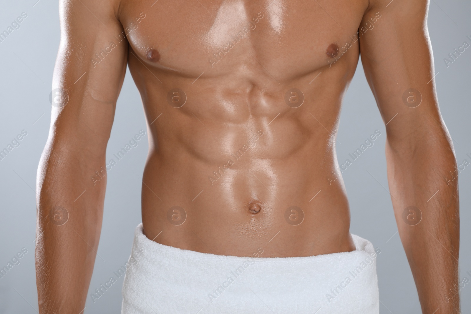 Shirtless man with slim body and towel wrapped around his hips on grey background, closeup Photo of Shirtless man with slim body and towel wrapped around his hips on grey background, closeup