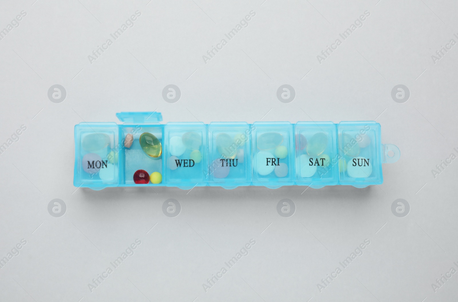 Photo of Plastic box with different pills on light grey background, top view