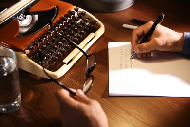 Man writing letter at wooden table indoors, closeup Photo of Man writing letter at wooden table indoors, closeup