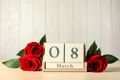 Wooden block calendar with date 8th of March and roses on table against light background, space for text. International Women's Day Photo of Wooden block calendar with date 8th of March and roses on table against light background, space for text. International Women's Day
