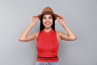 Beautiful young woman with straw hat on light grey background Photo of Beautiful young woman with straw hat on light grey background