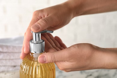 Woman using liquid soap dispenser, closeup view Photo of Woman using liquid soap dispenser, closeup view