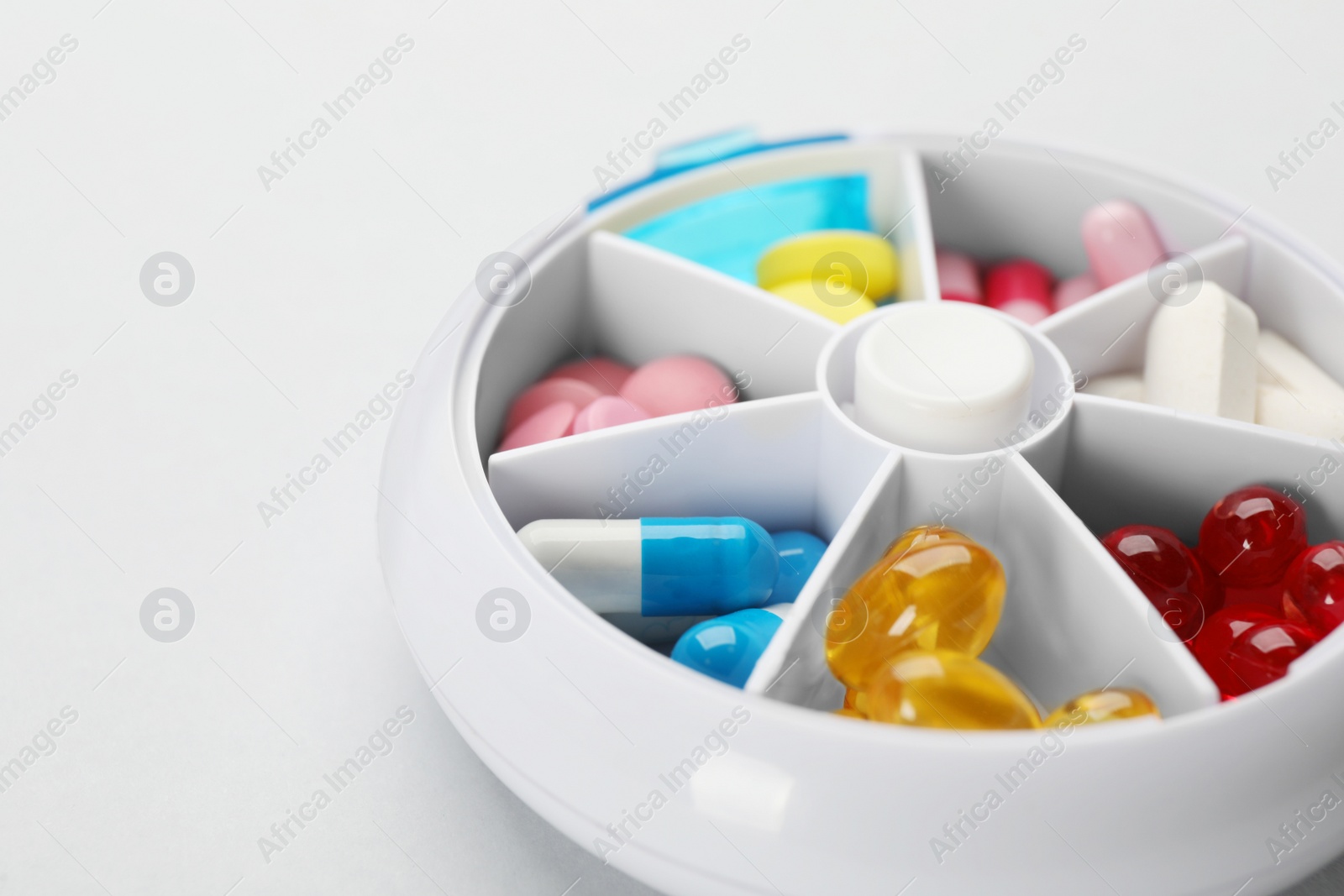 Plastic box with different pills on light grey background, closeup Photo of Plastic box with different pills on light grey background, closeup