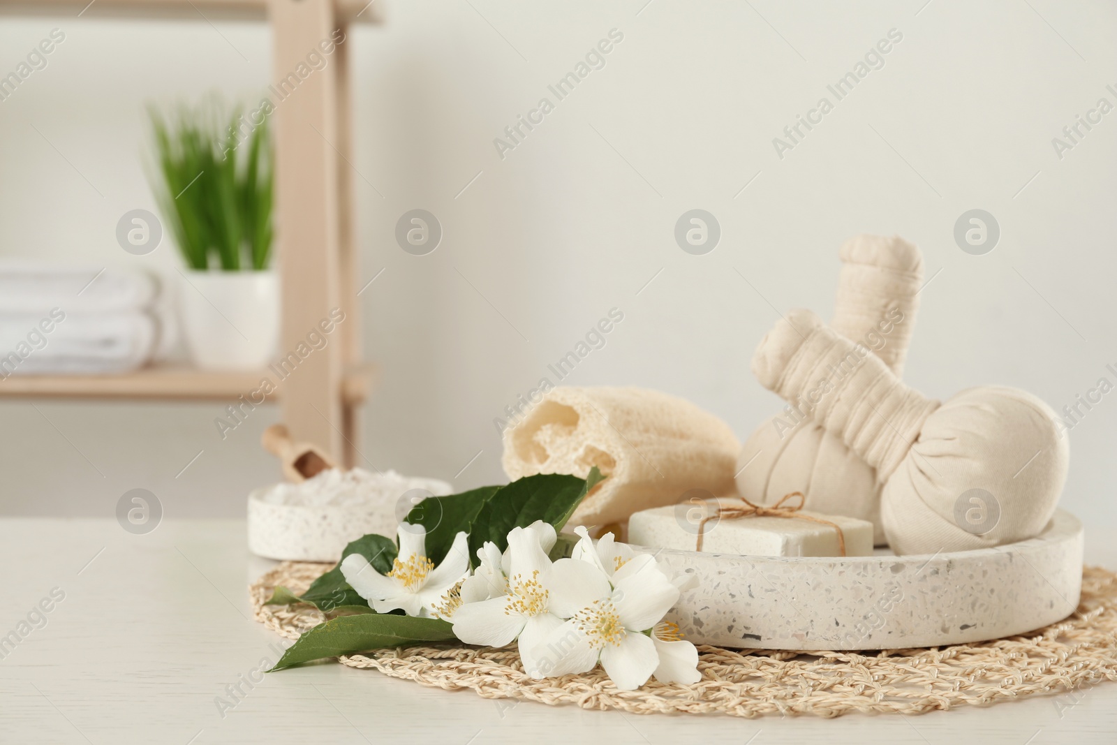 Beautiful jasmine flowers, herbal bags and soap bar on white wooden table indoors, space for text Photo of Beautiful jasmine flowers, herbal bags and soap bar on white wooden table indoors, space for text