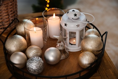 Burning candles, lantern and Christmas balls on wooden table indoors, closeup Photo of Burning candles, lantern and Christmas balls on wooden table indoors, closeup