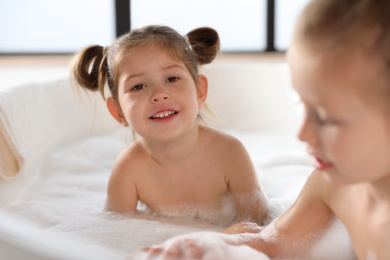 Cute little sisters taking bubble bath together Photo of Cute little sisters taking bubble bath together