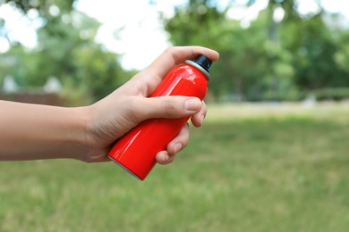 Woman with bottle of insect repellent spray outdoors, closeup Photo of Woman with bottle of insect repellent spray outdoors, closeup