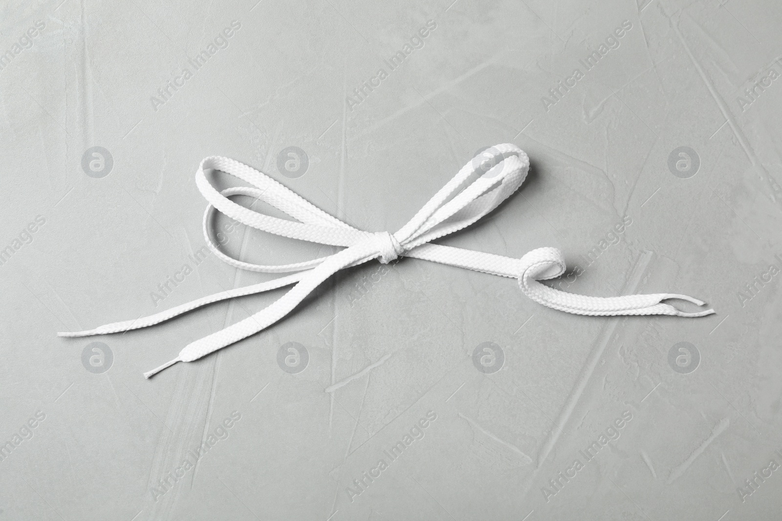 White shoelaces on light grey stone background, top view Photo of White shoelaces on light grey stone background, top view