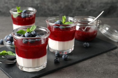 Delicious panna cotta with fruit coulis and fresh blueberries served on grey table. Space for text Photo of Delicious panna cotta with fruit coulis and fresh blueberries served on grey table. Space for text