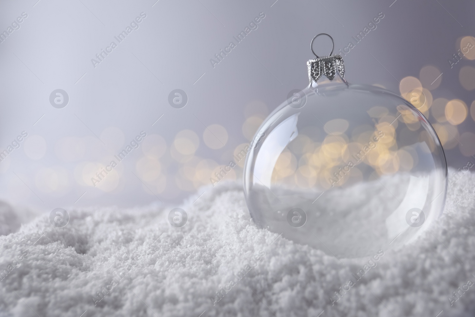 Transparent Christmas ball on snow against blurred fairy lights, space for text Photo of Transparent Christmas ball on snow against blurred fairy lights, space for text