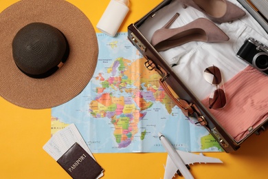 Flat lay composition with packed suitcase and travel accessories on yellow background. Summer vacation Photo of Flat lay composition with packed suitcase and travel accessories on yellow background. Summer vacation