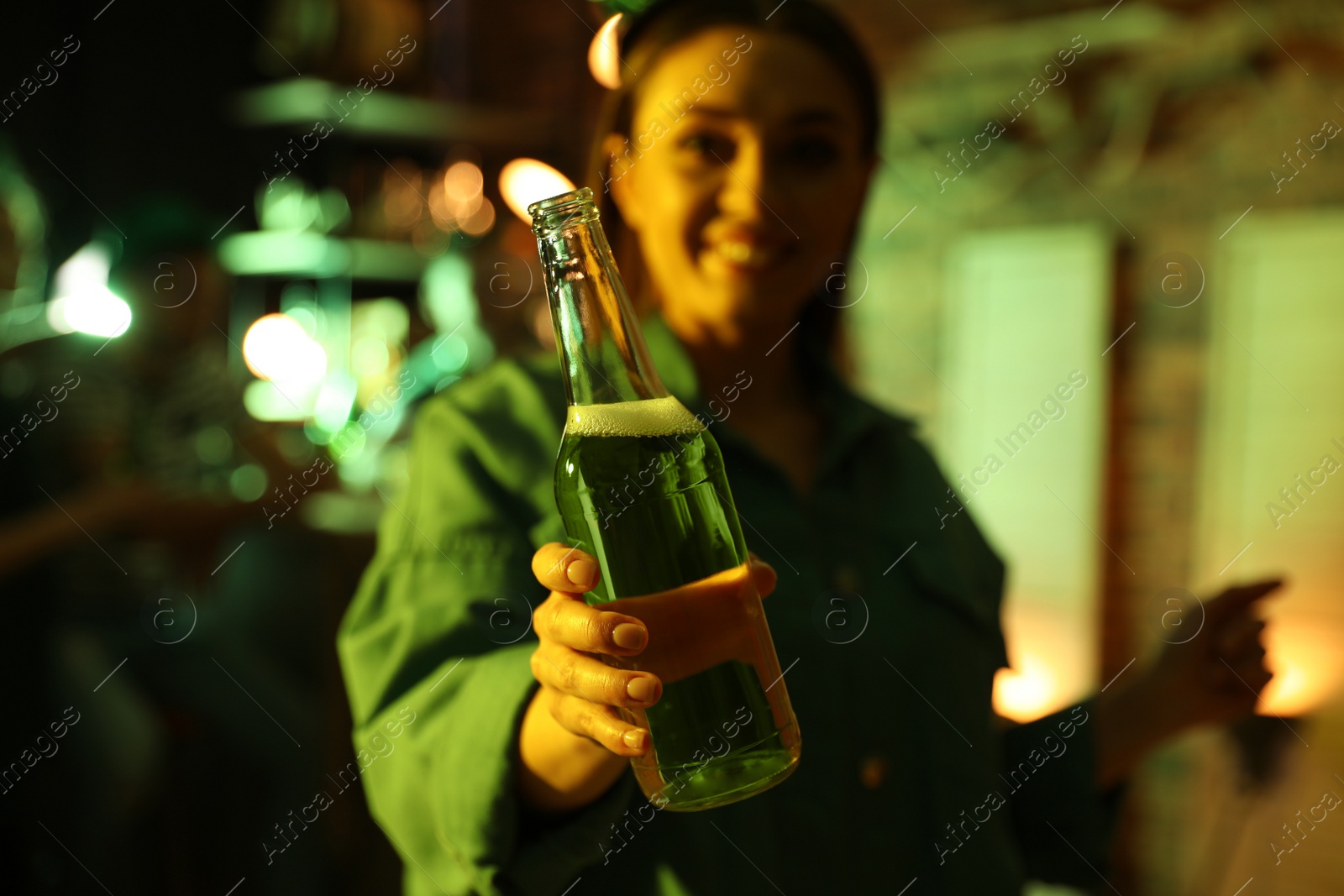Woman with beer celebrating St Patrick's day in pub, focus on hand Photo of Woman with beer celebrating St Patrick's day in pub, focus on hand