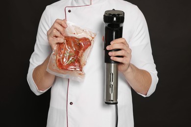 Chef holding sous vide cooker and meat in vacuum pack on black background, closeup Photo of Chef holding sous vide cooker and meat in vacuum pack on black background, closeup