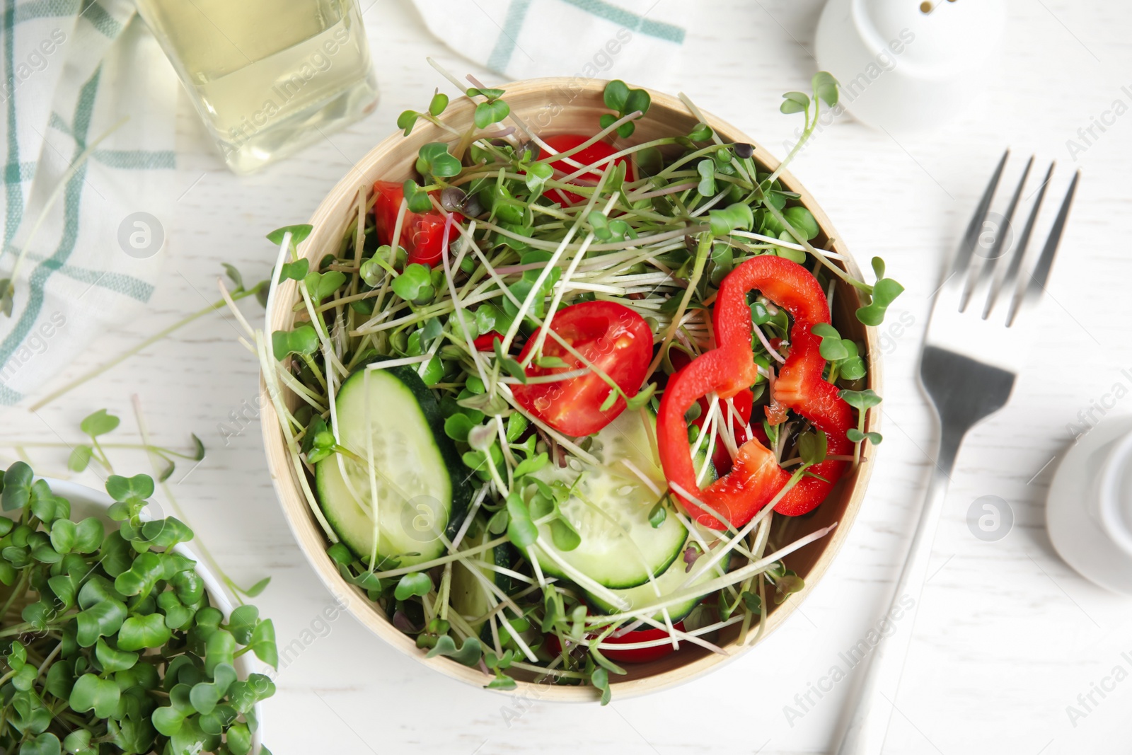 Salad with fresh organic microgreen in bowl on white table, flat lay Photo of Salad with fresh organic microgreen in bowl on white table, flat lay