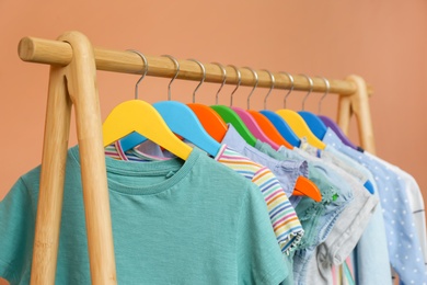 Photo of Rack with stylish children clothes on beige background, closeup