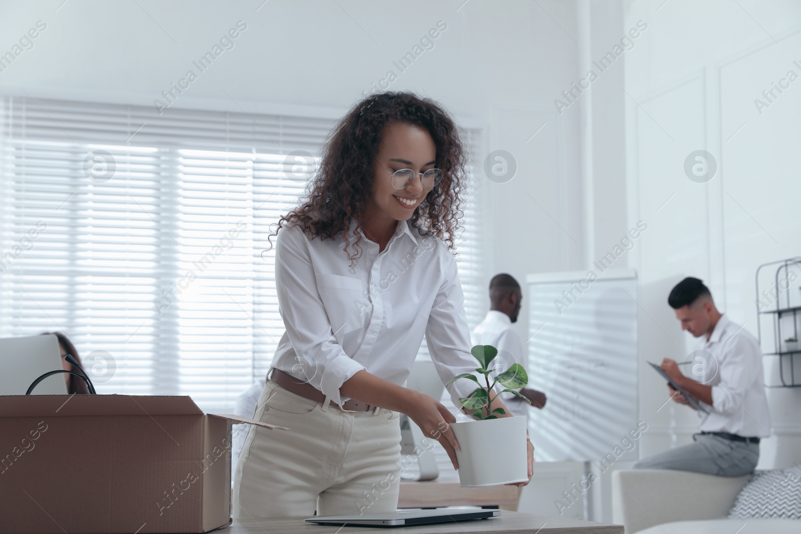 New coworker unpacking box with personal items at workplace in office Photo of New coworker unpacking box with personal items at workplace in office