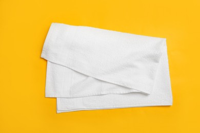 Folded white beach towel on yellow background, top view Photo of Folded white beach towel on yellow background, top view