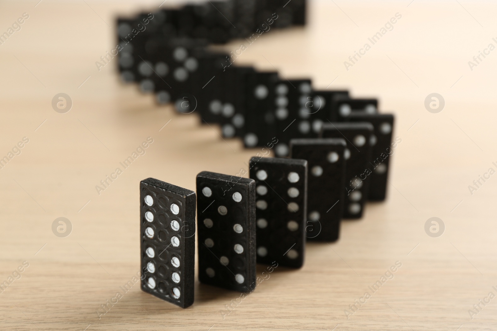 Black domino tiles with white pips on wooden table Photo of Black domino tiles with white pips on wooden table