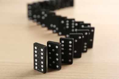 Black domino tiles with white pips on wooden table Photo of Black domino tiles with white pips on wooden table