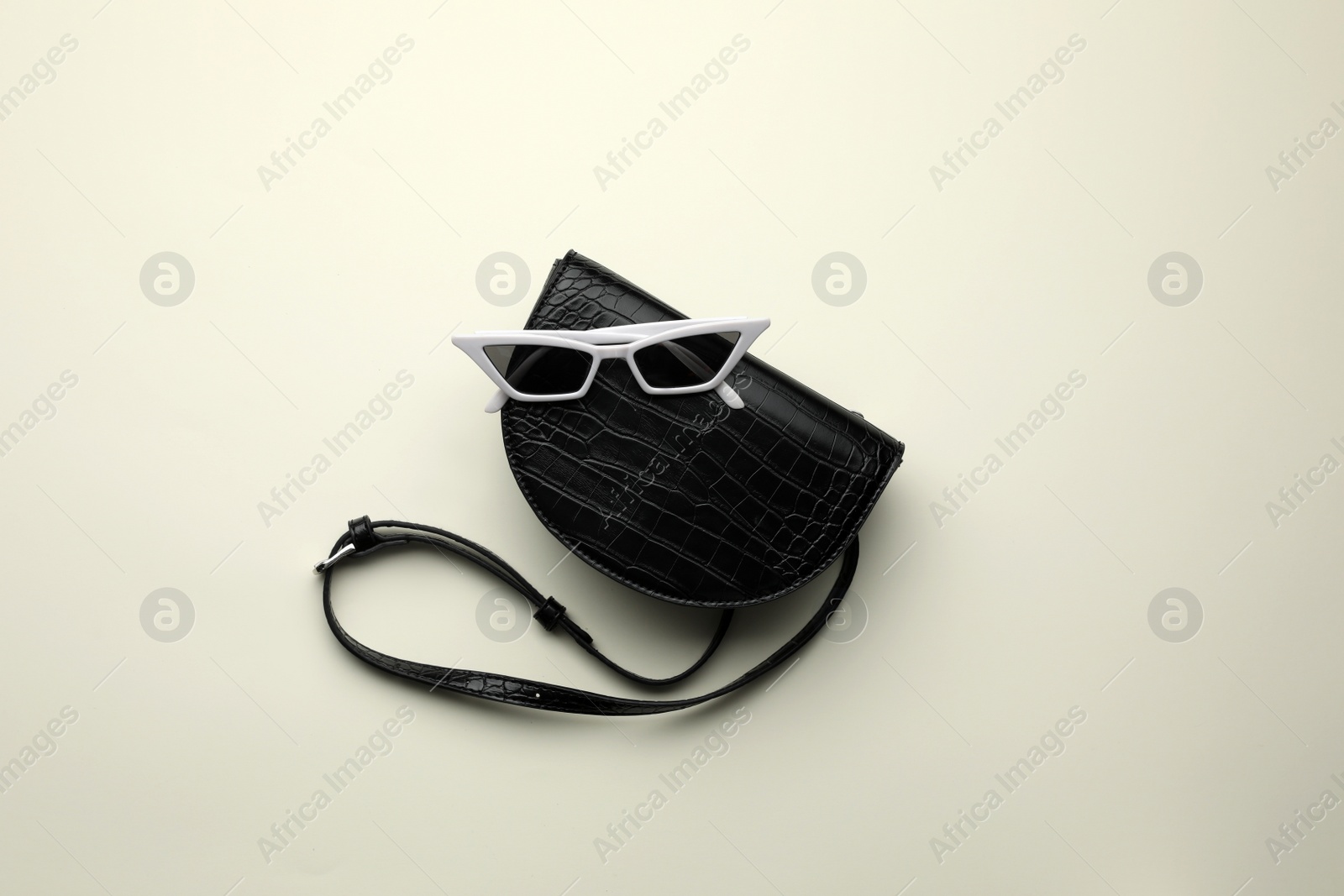Stylish woman's bag and sunglasses on light background, top view Photo of Stylish woman's bag and sunglasses on light background, top view