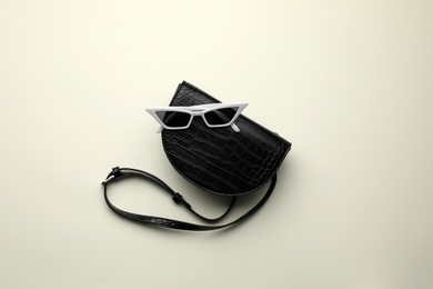 Stylish woman's bag and sunglasses on light background, top view Photo of Stylish woman's bag and sunglasses on light background, top view