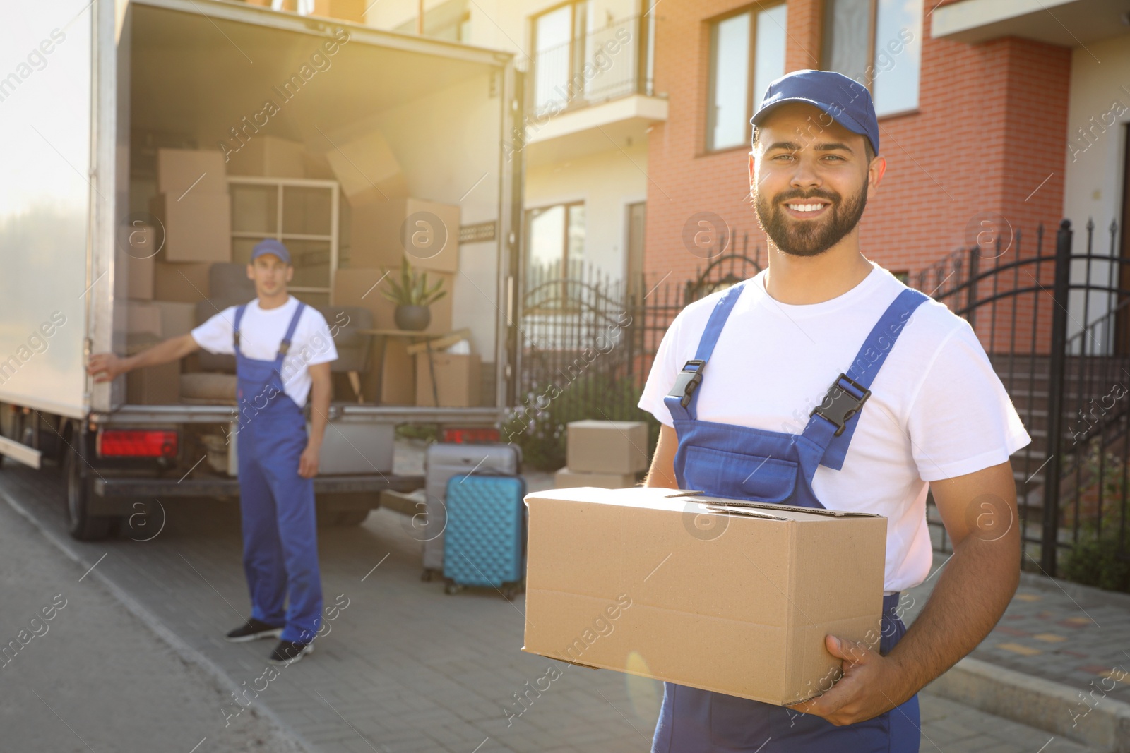 Workers unloading boxes from van outdoors. Moving service Photo of Workers unloading boxes from van outdoors. Moving service