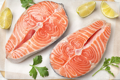 Fresh raw salmon with parsley and lime on parchment, flat lay. Fish delicacy Photo of Fresh raw salmon with parsley and lime on parchment, flat lay. Fish delicacy