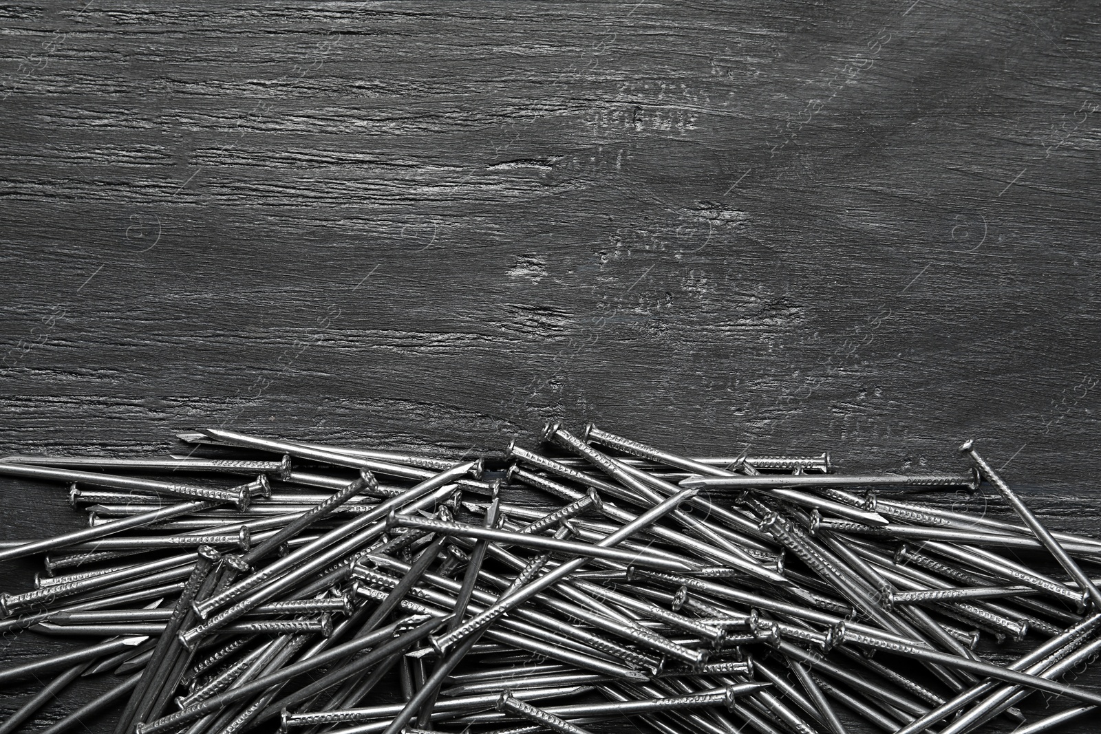 Pile of metal nails on grey wooden background, flat lay. Space for text Photo of Pile of metal nails on grey wooden background, flat lay. Space for text