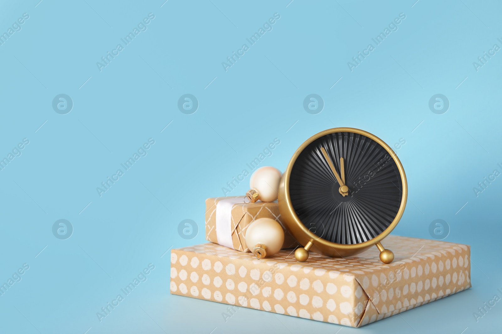 Stylish clock with Christmas decor on light blue background, space for text. New Year countdown Photo of Stylish clock with Christmas decor on light blue background, space for text. New Year countdown