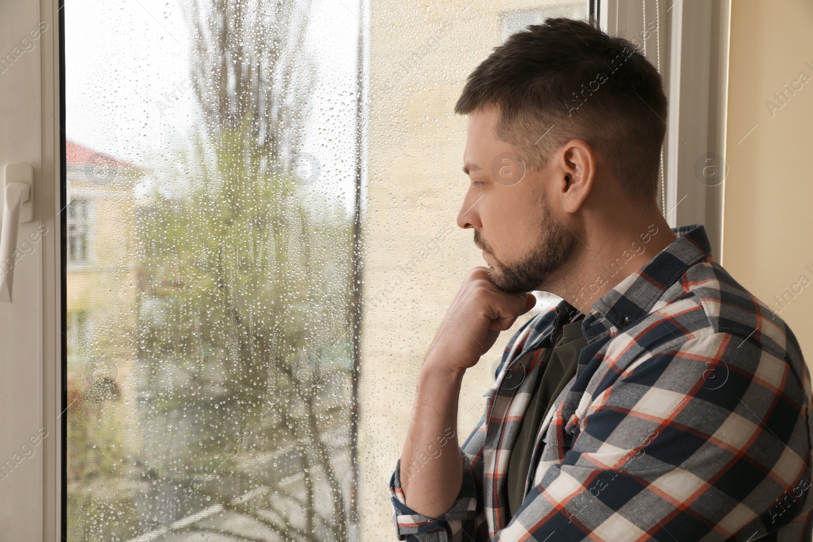 Depressed man near window at home. Space for text Photo of Depressed man near window at home. Space for text