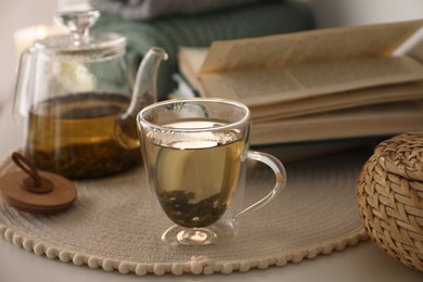 Glass teapot and cup of hot tea on table in room. Cozy home atmosphere Photo of Glass teapot and cup of hot tea on table in room. Cozy home atmosphere