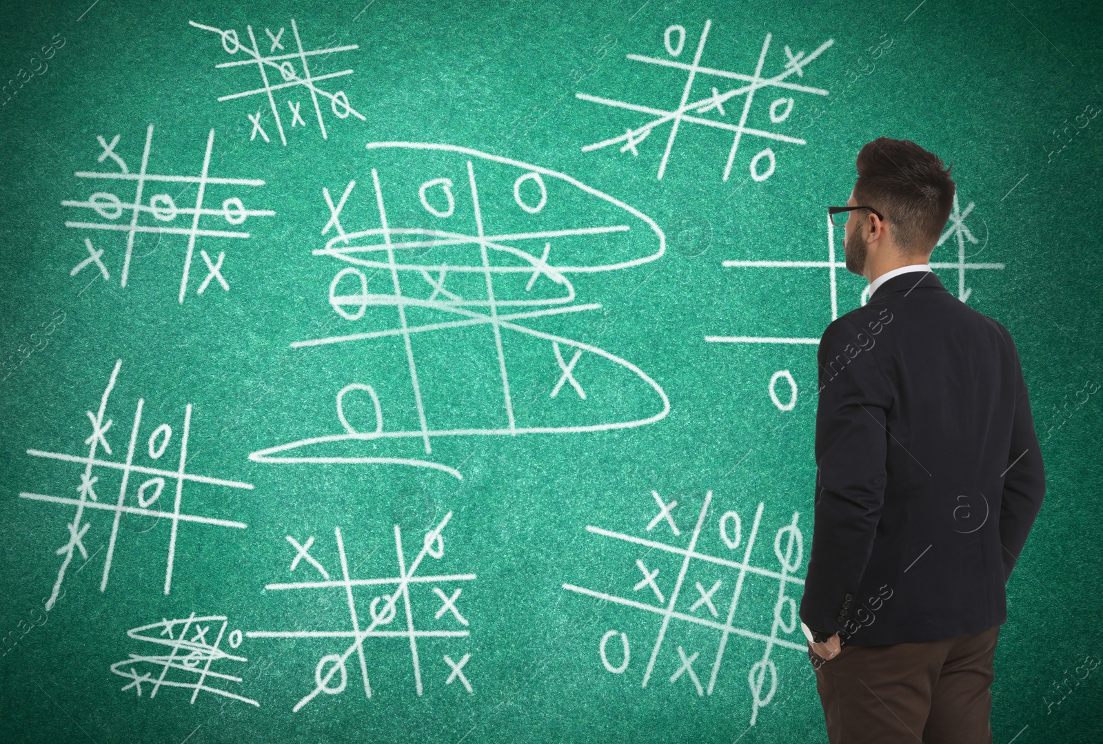 Young businessman near green chalkboard with drawn tic tac toe game Image of Young businessman near green chalkboard with drawn tic tac toe game