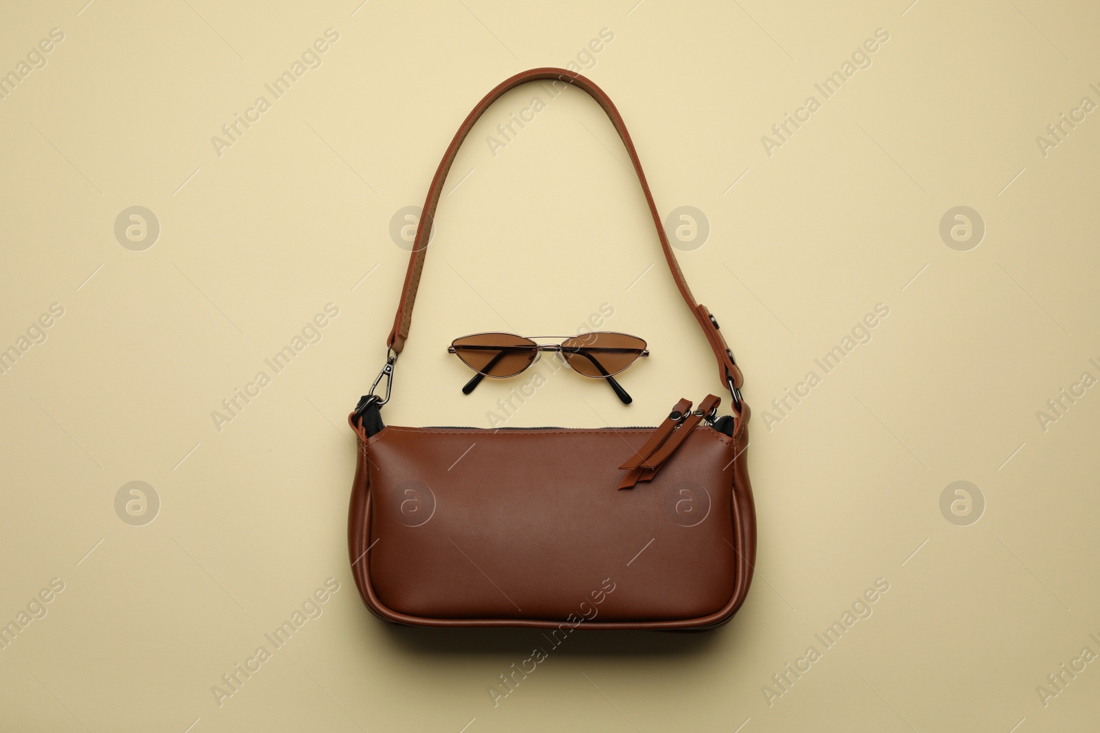 Stylish woman's bag and sunglasses on beige background, flat lay Photo of Stylish woman's bag and sunglasses on beige background, flat lay