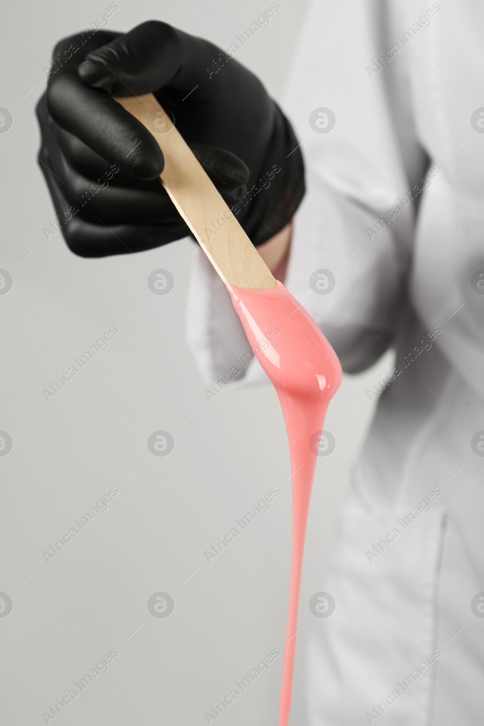 Woman in gloves holding spatula with hot depilatory wax, closeup Photo of Woman in gloves holding spatula with hot depilatory wax, closeup