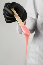 Woman in gloves holding spatula with hot depilatory wax, closeup Photo of Woman in gloves holding spatula with hot depilatory wax, closeup