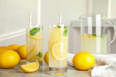 Cool freshly made lemonade and fruits on grey table Photo of Cool freshly made lemonade and fruits on grey table