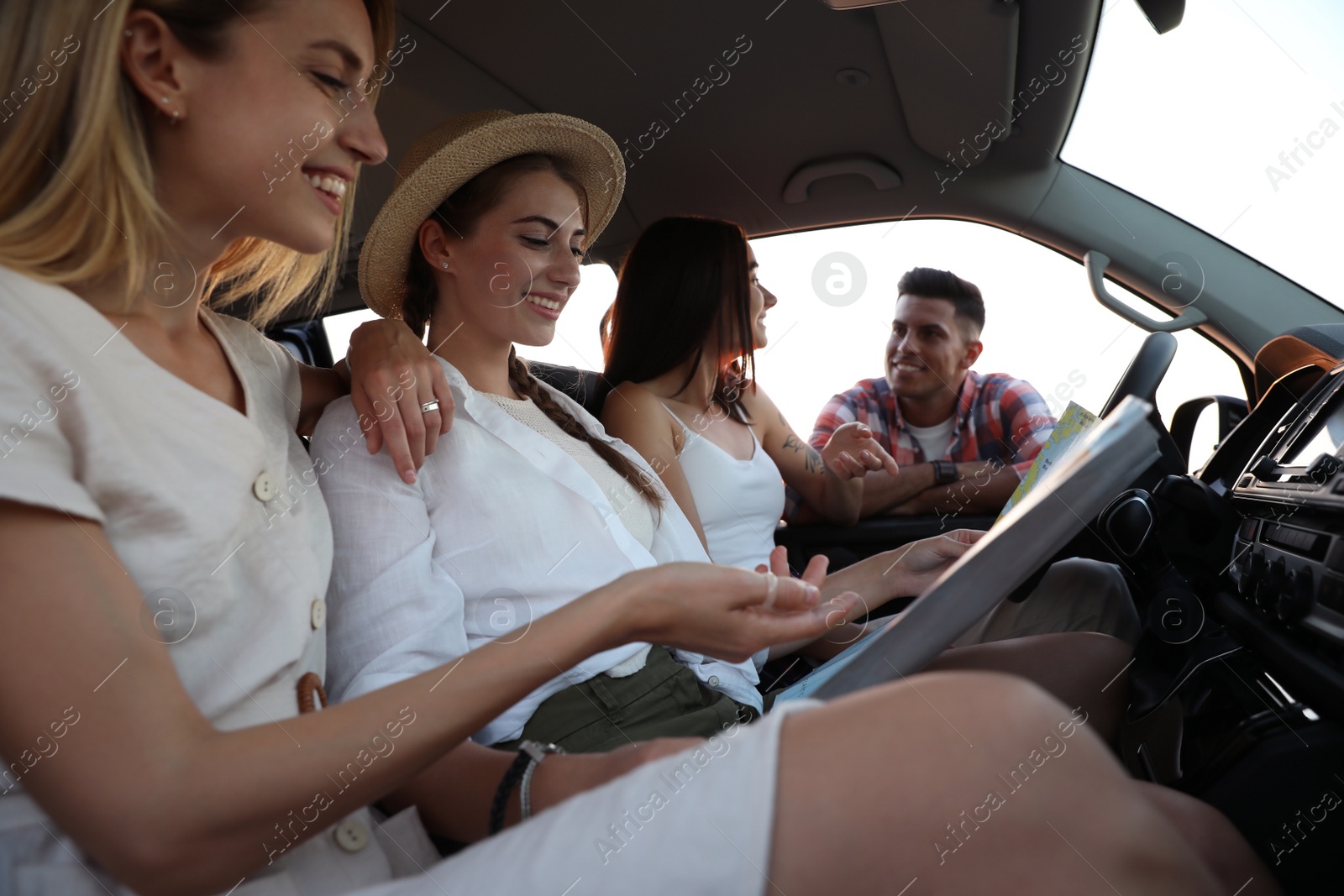 Happy friends with map in car on road trip Photo of Happy friends with map in car on road trip