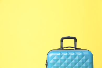 Photo of Stylish blue suitcase on yellow background. Space for text