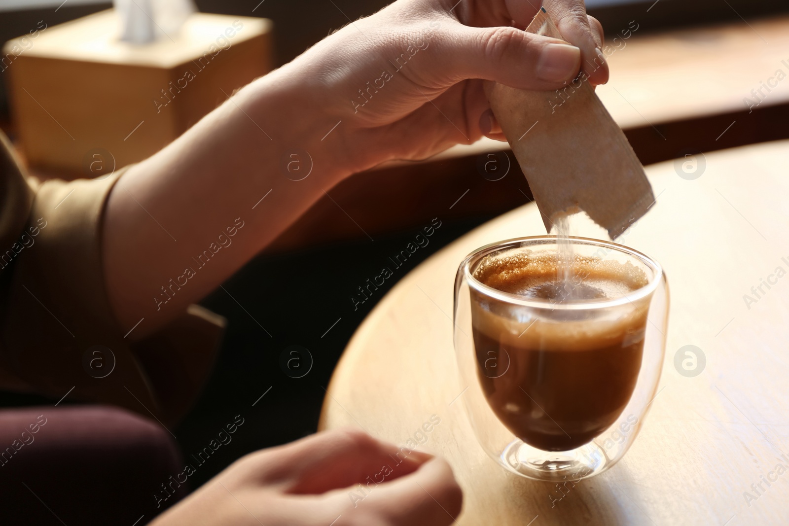 Woman adding sugar to aromatic coffee at table in cafe, closeup Photo of Woman adding sugar to aromatic coffee at table in cafe, closeup