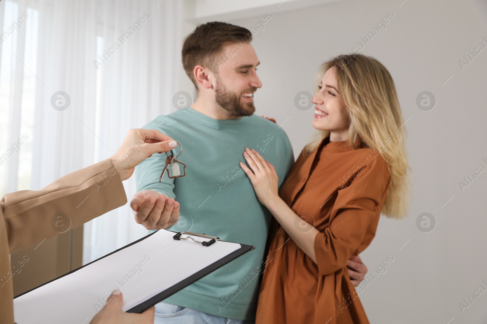 Real estate agent giving key to happy young couple in new house, focus on hands Photo of Real estate agent giving key to happy young couple in new house, focus on hands