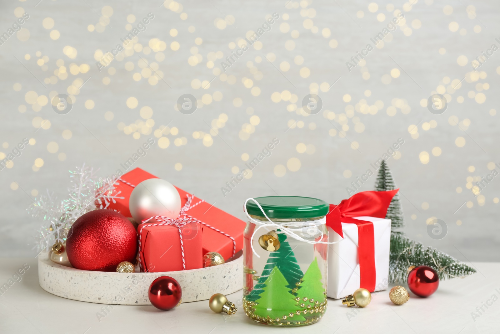 Handmade snow globe and Christmas decorations on light table, space for text Photo of Handmade snow globe and Christmas decorations on light table, space for text