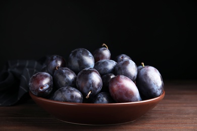 Delicious ripe plums in bowl on wooden table Photo of Delicious ripe plums in bowl on wooden table
