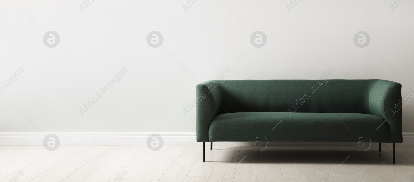 Comfortable green sofa near white wall indoors, space for text. Interior design Photo of Comfortable green sofa near white wall indoors, space for text. Interior design