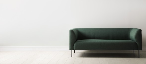 Comfortable green sofa near white wall indoors, space for text. Interior design Photo of Comfortable green sofa near white wall indoors, space for text. Interior design