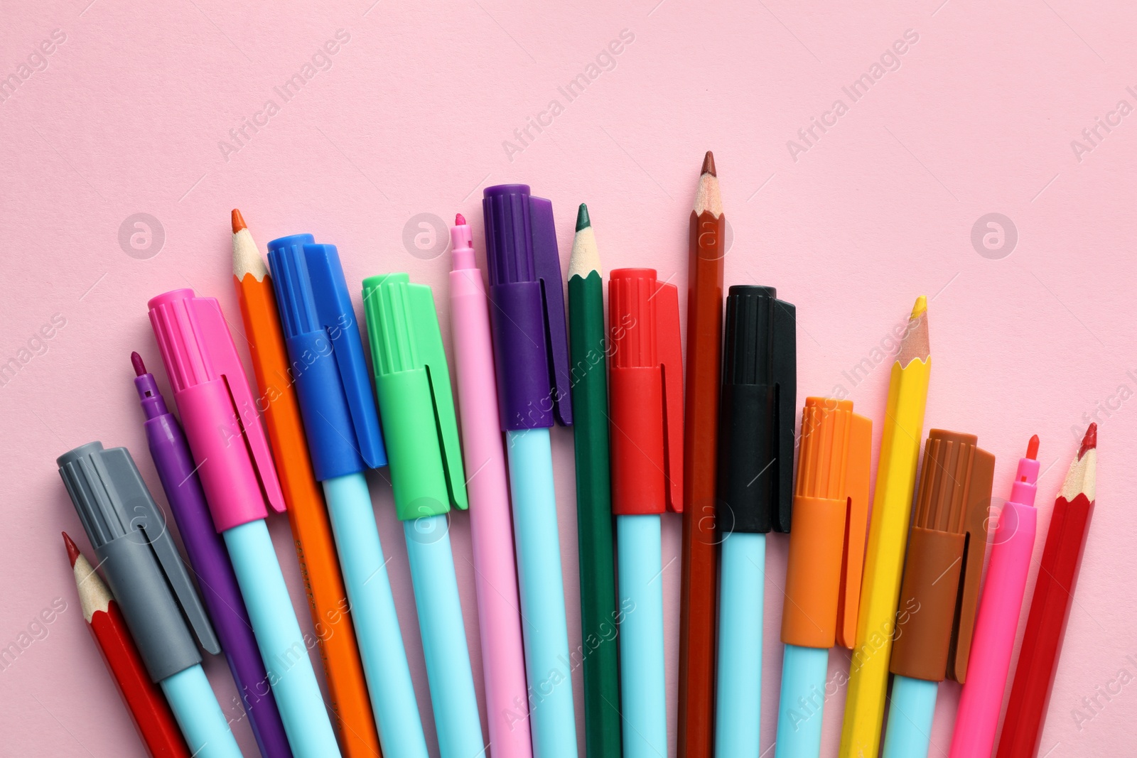 Different colorful pencils and felt tip pens on pink background, flat lay. Diversity concept Photo of Different colorful pencils and felt tip pens on pink background, flat lay. Diversity concept