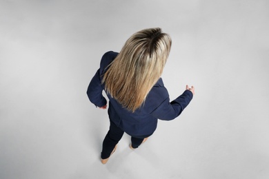 Young woman on grey background, back view Photo of Young woman on grey background, back view