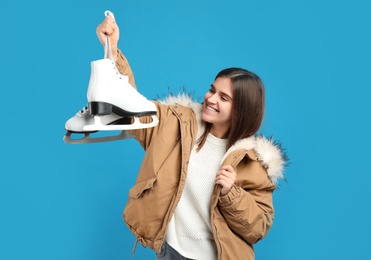 Photo of Happy woman with ice skates on light blue background