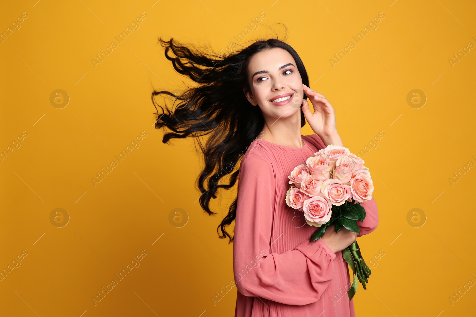 Portrait of smiling woman with beautiful bouquet on orange background. Space for text Photo of Portrait of smiling woman with beautiful bouquet on orange background. Space for text