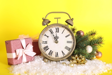 Vintage alarm clock with Christmas decor on yellow background. New Year countdown Photo of Vintage alarm clock with Christmas decor on yellow background. New Year countdown
