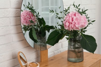 Beautiful pink hortensia flowers in vase on dressing table indoors Photo of Beautiful pink hortensia flowers in vase on dressing table indoors